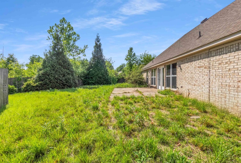 Rear exterior featuring a concrete patio, brick siding, and multiple windows