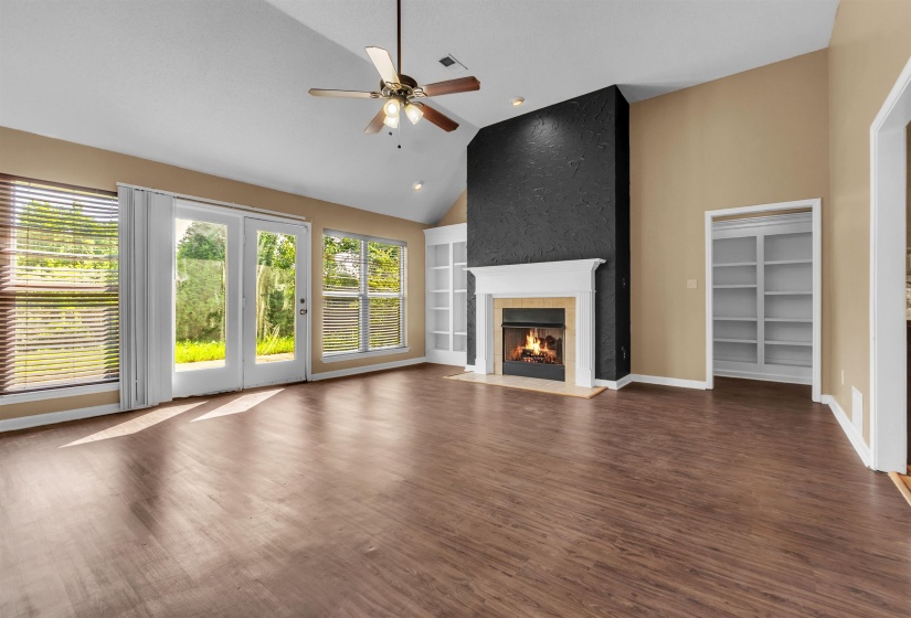 Spacious living area featuring wood-finish flooring, a vaulted ceiling, and a ceiling fan