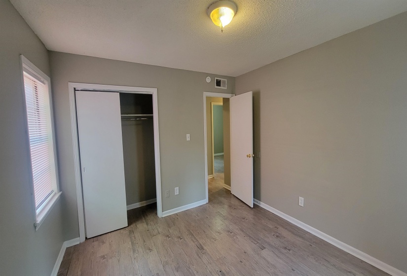 Unfurnished bedroom with a textured ceiling, light wood-type flooring, and a closet