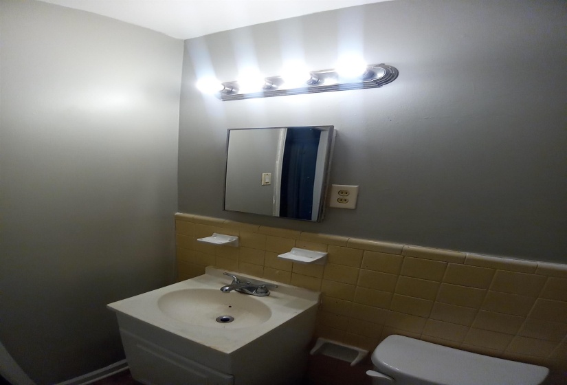 Bathroom with toilet, sink, and tile walls