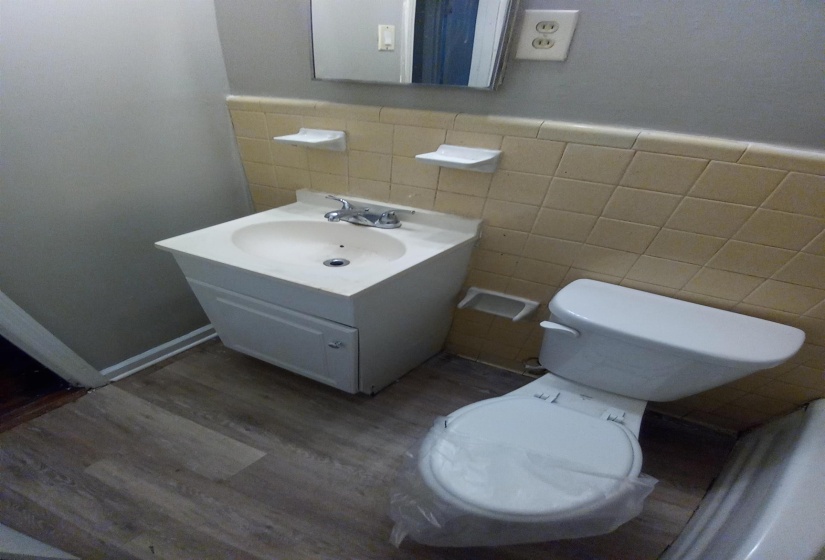 Bathroom with wood-type flooring, vanity, toilet, and tile walls