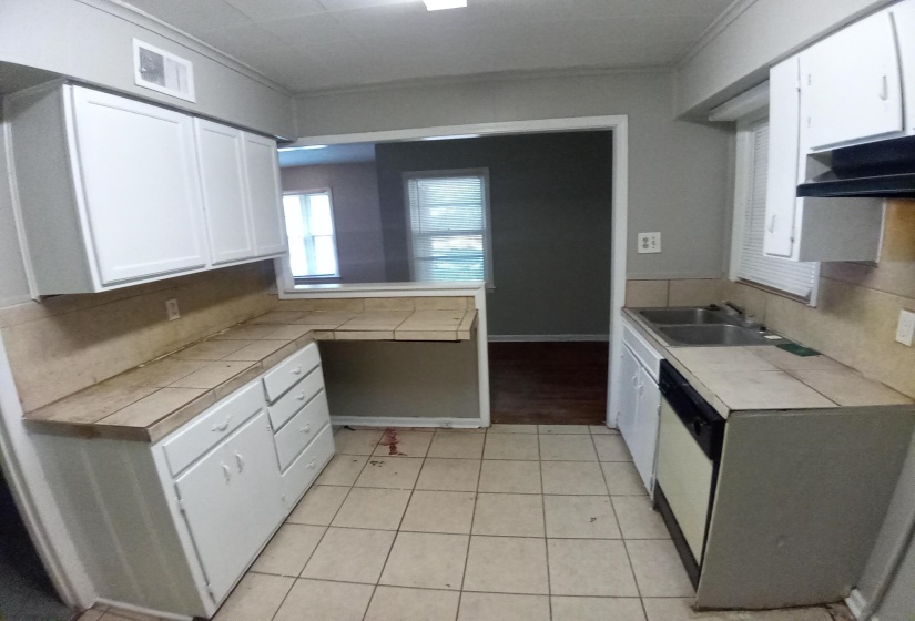 Kitchen featuring crown molding, sink, tile countertops, dishwasher, and white cabinets