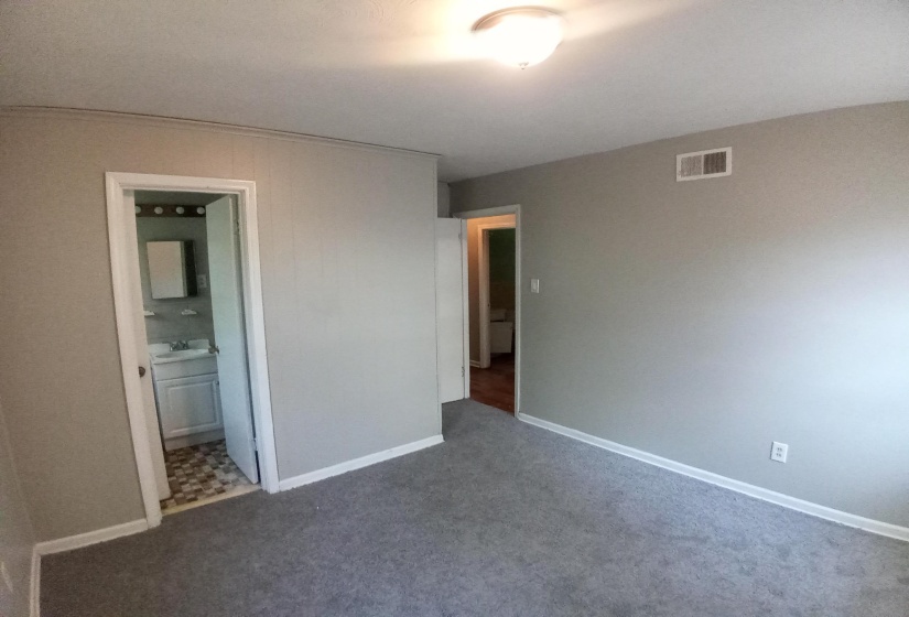 Unfurnished bedroom featuring ensuite bathroom, sink, and dark colored carpet