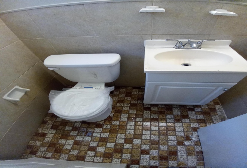 Bathroom featuring vanity, tile walls, and toilet