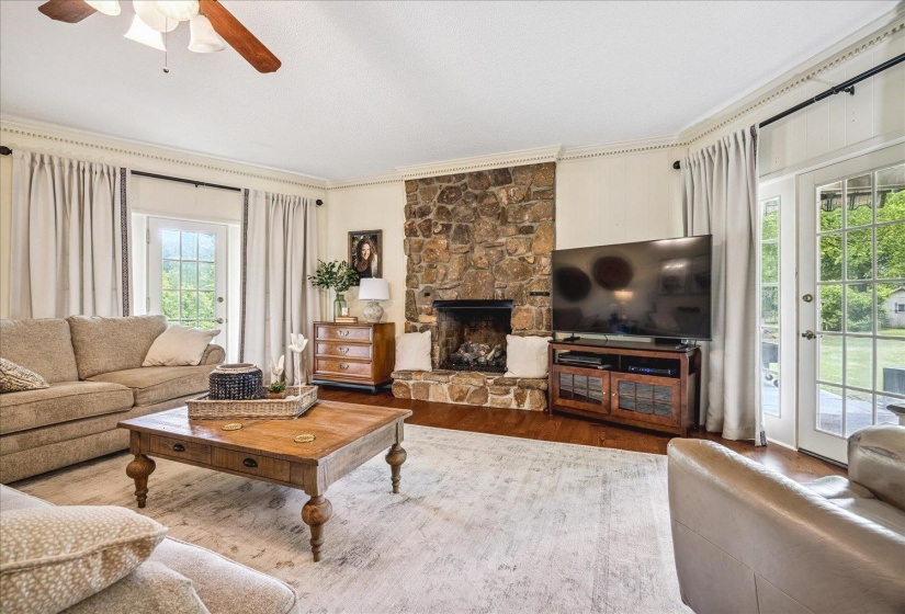 Living area featuring a stone-clad fireplace and wood-finish flooring