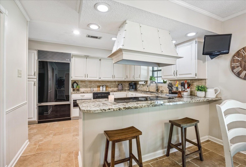 Kitchen featuring white shaker cabinetry, stone tile backsplash, granite countertops, and recessed lighting