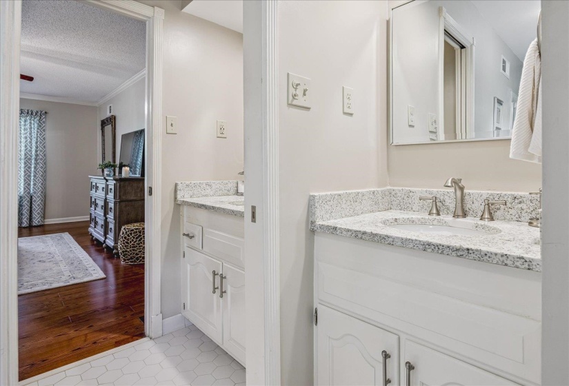 Dual vanity area featuring white cabinetry with brushed nickel hardware, speckled countertops, and undermount sinks with brushed nickel faucets
