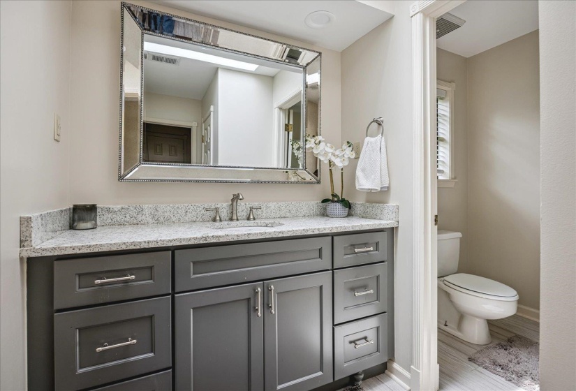 Vanity featuring shaker-style cabinetry with chrome hardware, a light-toned countertop, and an undermount sink with a brushed nickel faucet