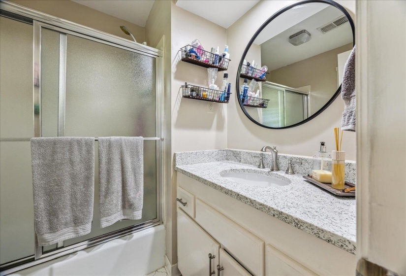 Bathroom vanity with a light speckled countertop, undermount sink, and brushed nickel faucet