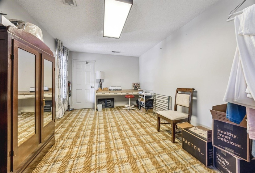 Spacious room featuring patterned carpeting, white walls, and a white paneled door