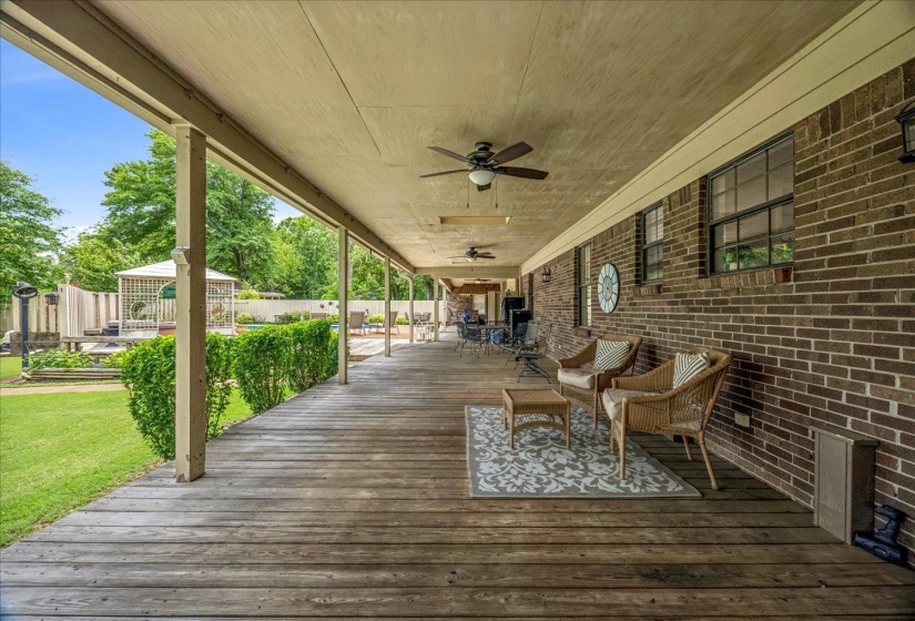 Expansive covered wood-finish deck with multiple ceiling fans and brick exterior