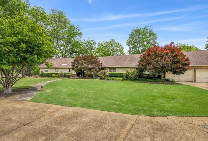 Spacious front lawn with mature trees and a curved walkway leading to the entrance