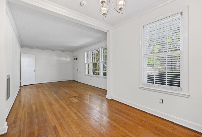 Hardwood flooring extends throughout this expansive room, featuring white walls and a white trim package
