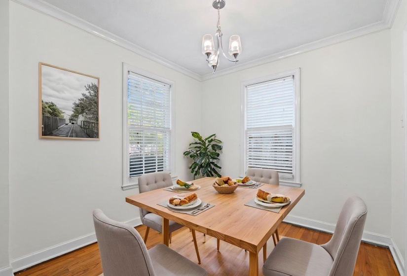 Dining area featuring wood-finish flooring, two large windows with blinds, a ceiling-mounted light fixture, and white crown molding