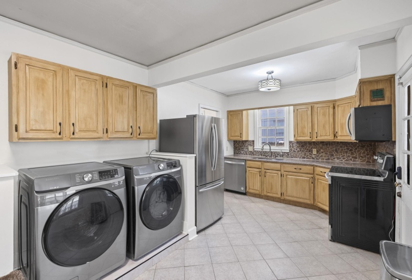 Kitchen and laundry area featuring light wood cabinetry, stone countertops, a tile backsplash, and tile flooring