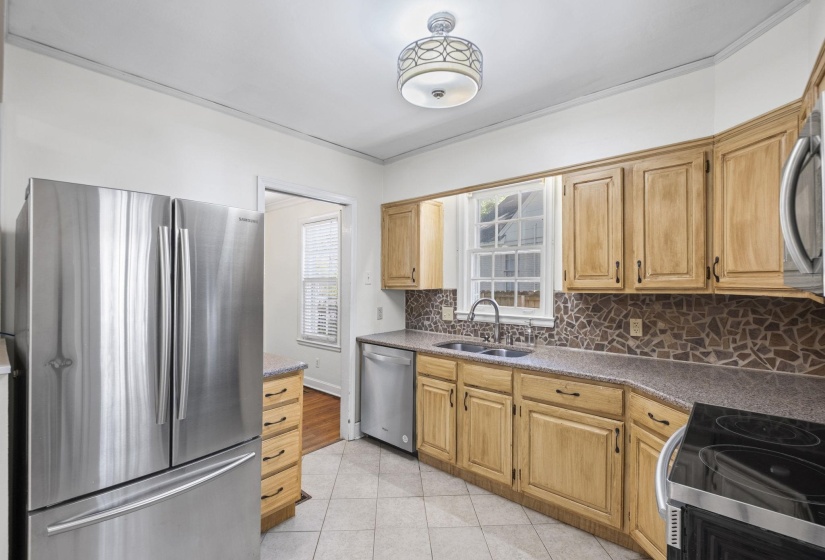 Kitchen featuring light wood cabinetry, a mosaic tile backsplash, and stone-finish countertops