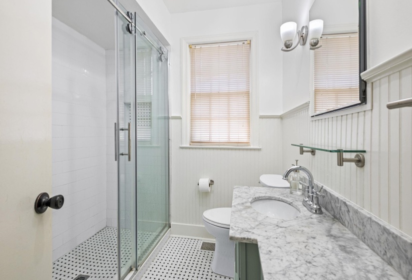 Bathroom featuring a glass-enclosed shower, beadboard wainscoting, and a single vanity with a stone countertop