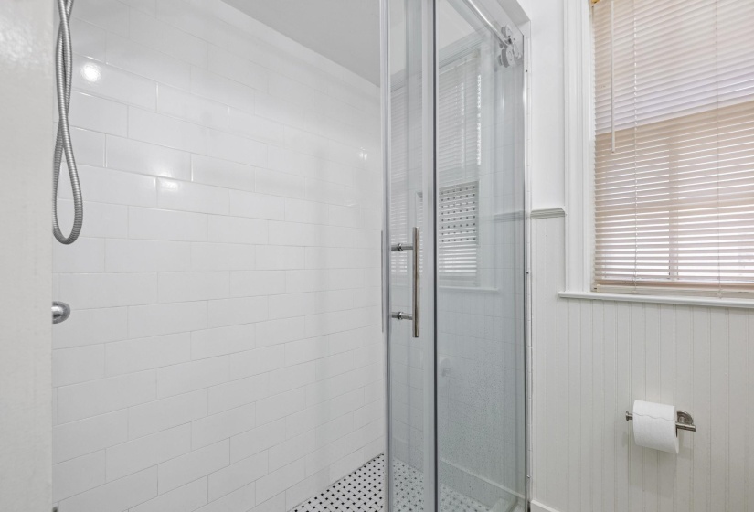 Glass-enclosed shower featuring subway tile surround and a hex tile floor