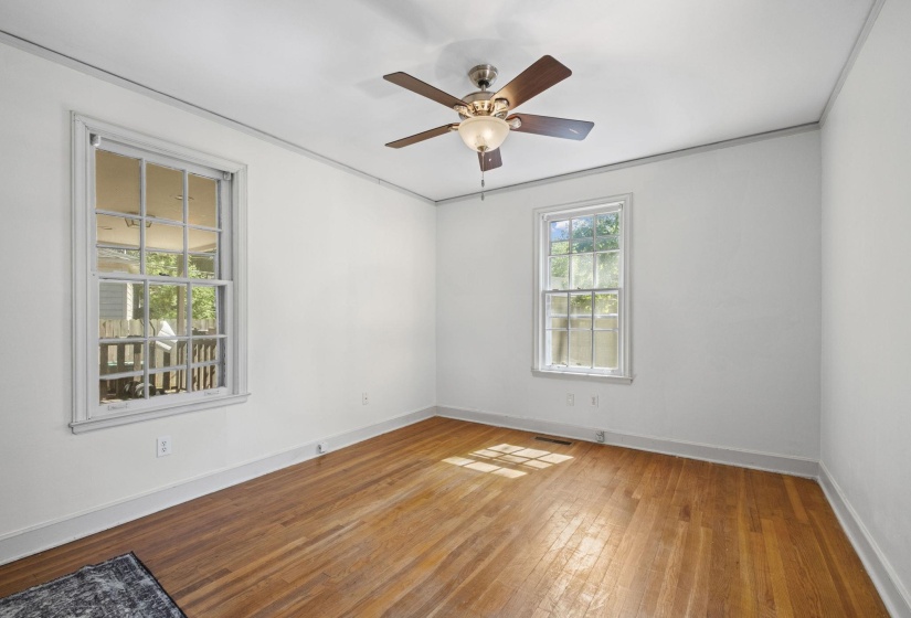 Spacious interior room featuring hardwood flooring and white baseboards