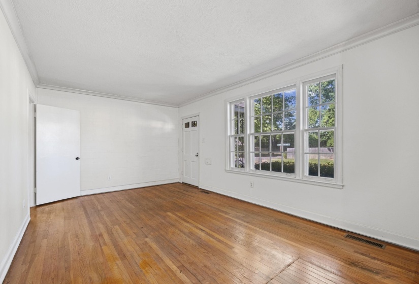 Hardwood flooring throughout, bright white walls, crown molding, and multiple paneled windows