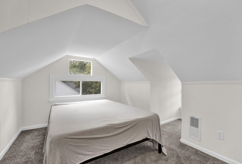 Attic space featuring sloped ceilings, a window array, carpeting, and baseboard trim