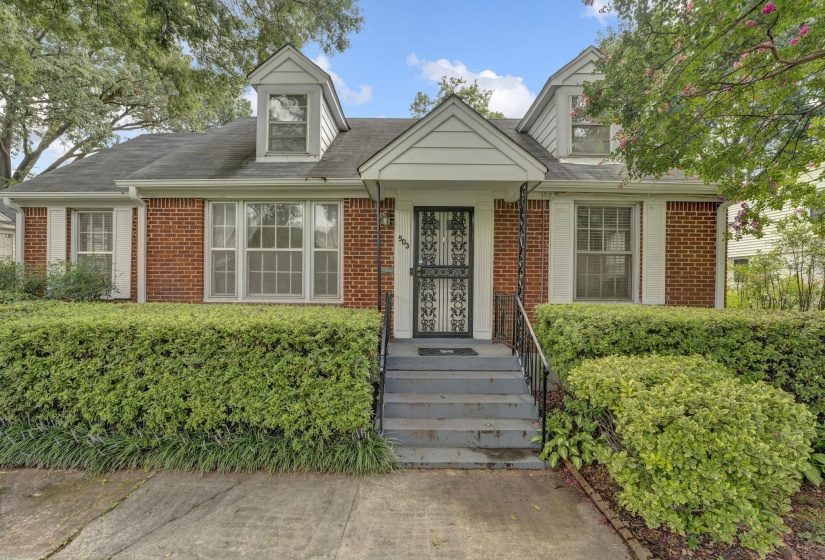 Brick facade home featuring white dormer windows and a covered entry