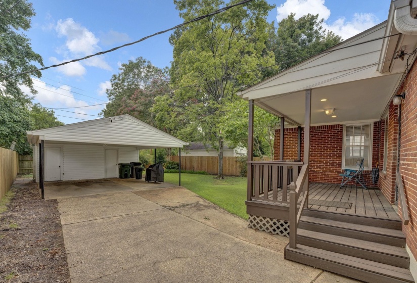 Expansive concrete driveway leading to a two-car carport