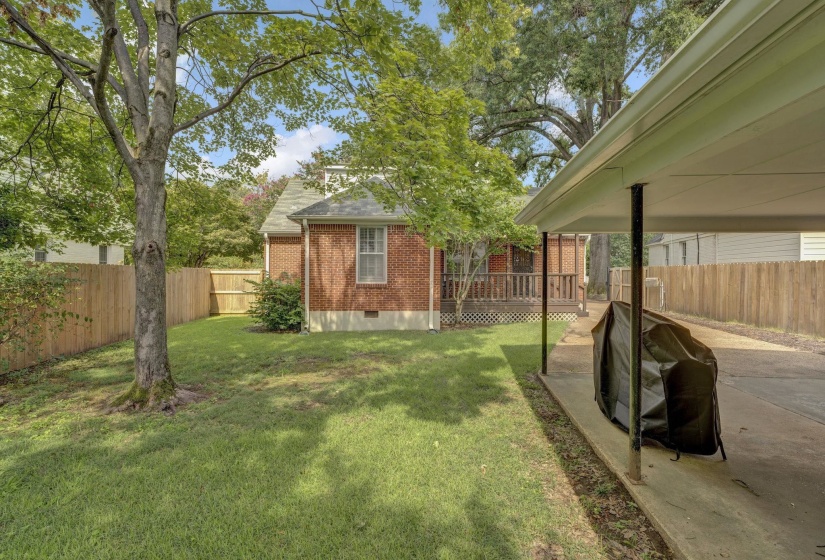 Expansive backyard featuring a manicured lawn, established trees, and a full privacy fence