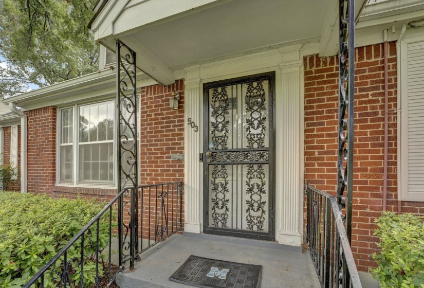 Brick exterior featuring a covered front porch with ornate wrought iron railings and security door