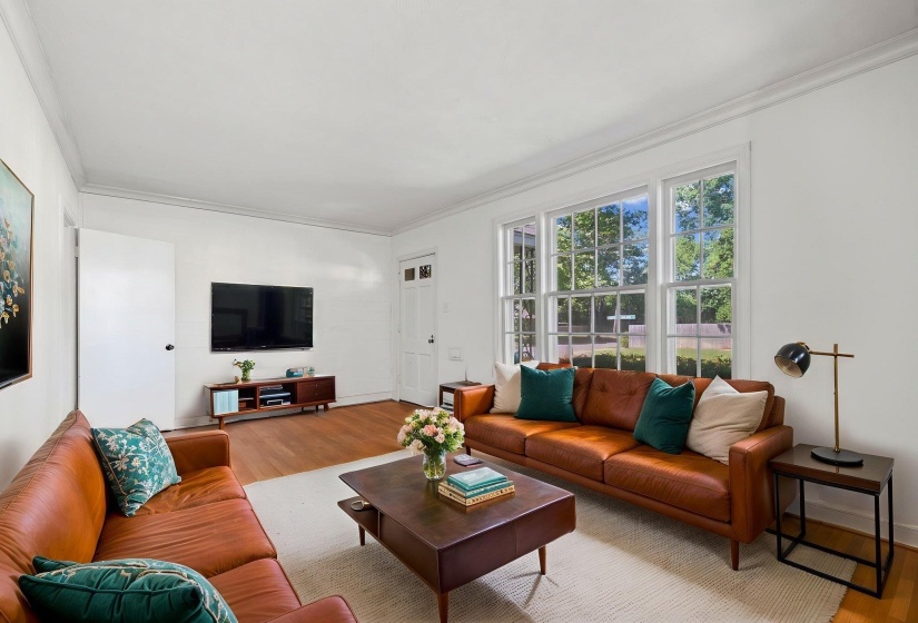 Bright living area featuring wood-finish flooring, white walls, and crown molding