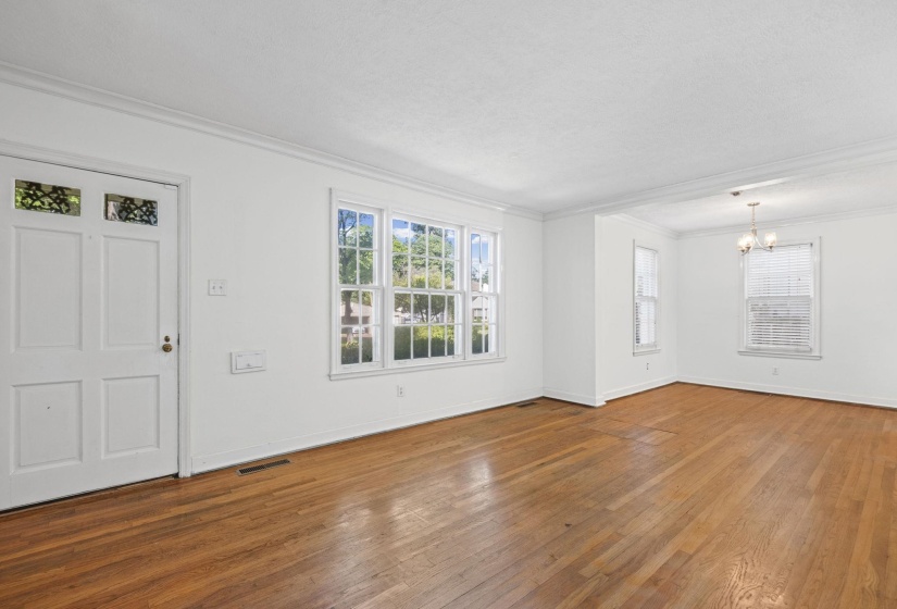 Spacious living area featuring wood-finish flooring, white walls, and multiple windows