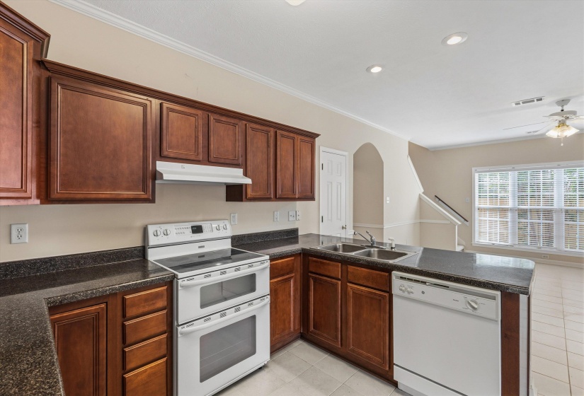 Kitchen featuring dark wood cabinetry, dark countertops, white double oven range, white dishwasher, and a double basin stainless steel sink