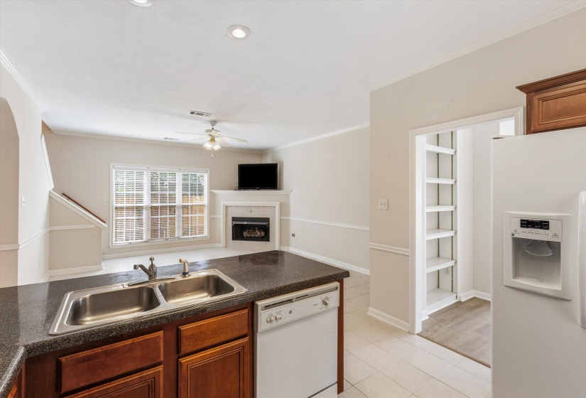 Kitchen with a double basin stainless steel sink, dark countertops, and wood-finish cabinetry