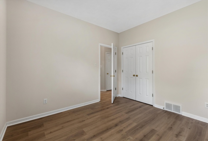 Room featuring wood-finish flooring, light neutral wall paint, and white baseboards
