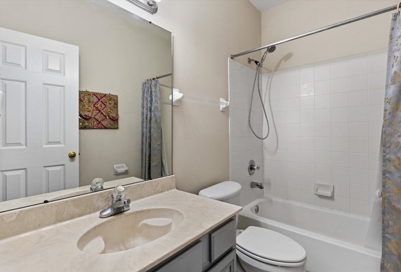 Bathroom vanity with an integrated sink and light-toned countertop, set against a full-width mirror