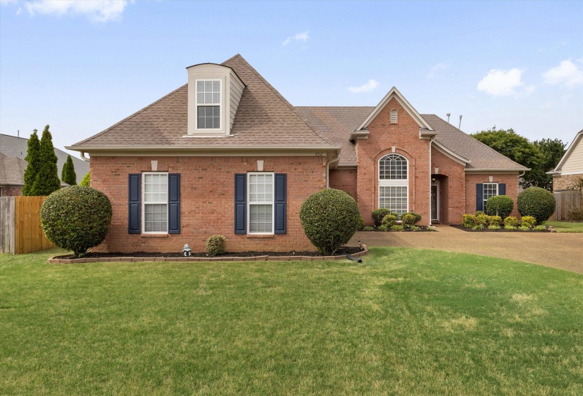 Brick exterior with dormer window, gabled entry, arched window, and landscaped front yard