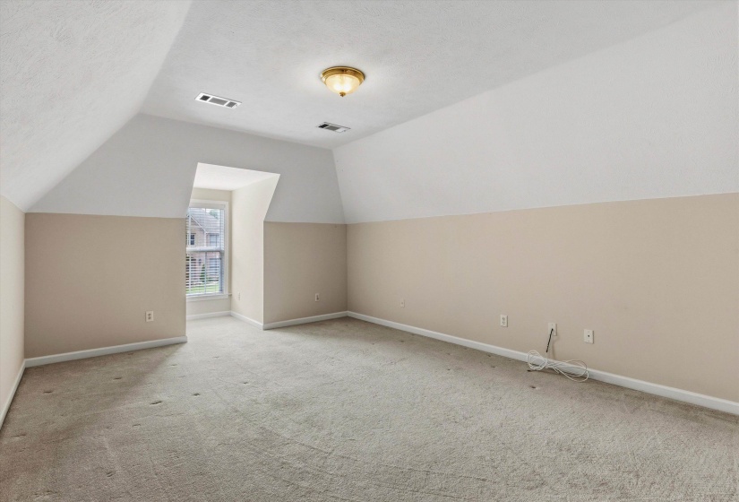 Carpeted room featuring a dormer window, neutral wall tones, white trim, and a ceiling-mounted light fixture