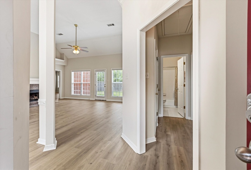 Spacious living area featuring vaulted ceilings, wood-finish flooring, and ample natural light from multiple windows
