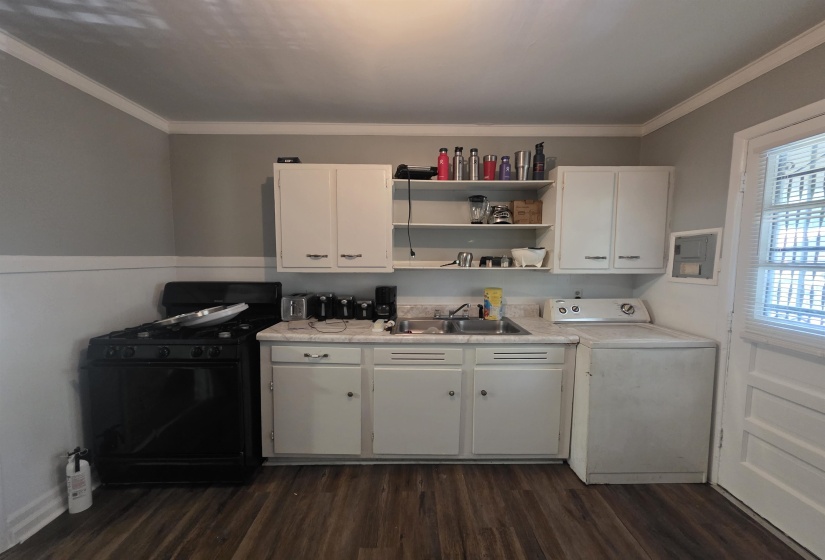 Kitchen area featuring wood-finish flooring, white cabinetry, a built-in sink, an electric range, and a built-in washer