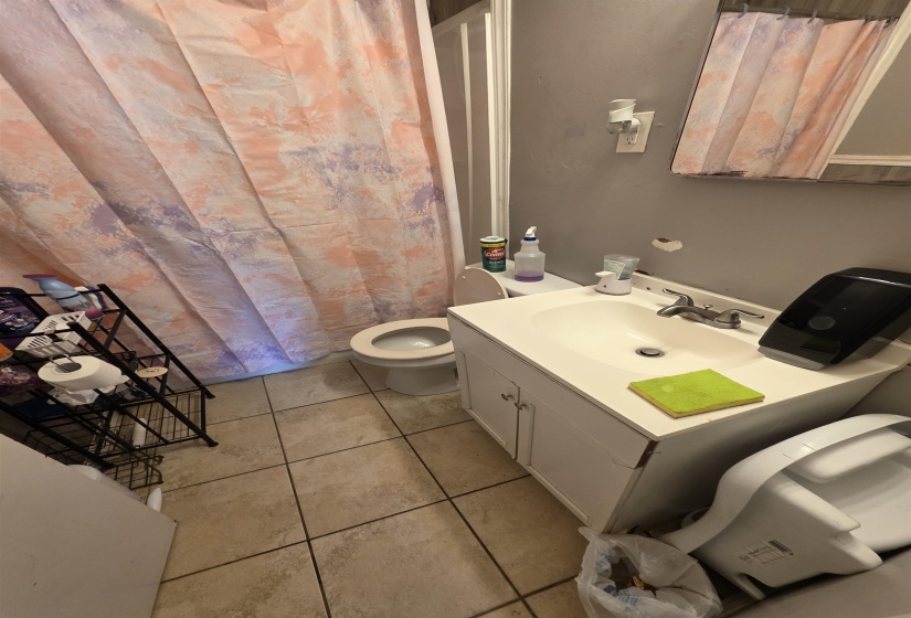 Bathroom with neutral-toned floor tile and a white vanity with an integrated sink