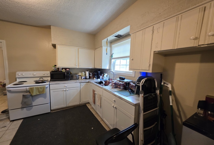 Kitchen featuring white cabinetry, a white electric range, and a corner sink with a window above