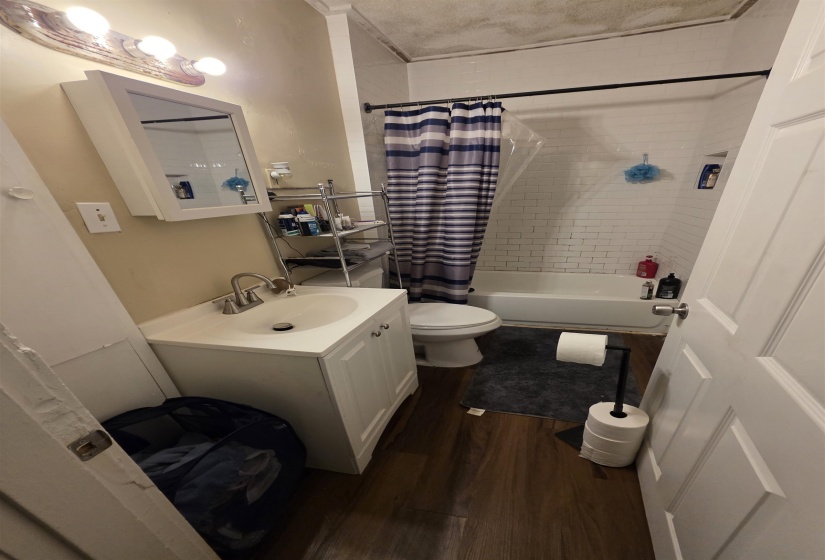 Bathroom featuring a white vanity with an integrated sink, brushed nickel faucet, and wood-finish flooring