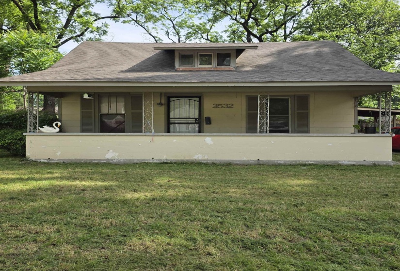 Front elevation featuring a covered porch with decorative metal columns, a dormer window, and a shingle roof
