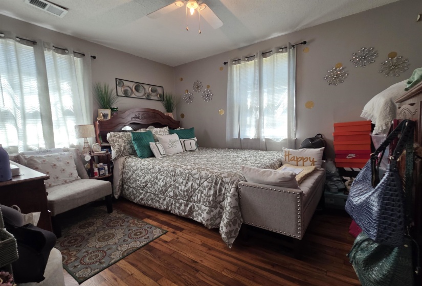 Hardwood-finish flooring featuring a ceiling fan, dual windows, and light-toned walls