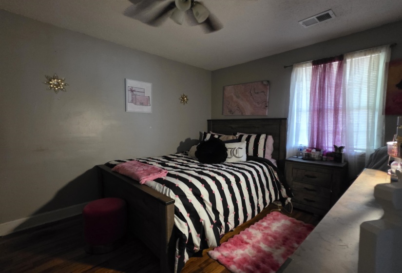Bedroom featuring wood-finish flooring, a ceiling fan with integrated lighting, and a window with blinds