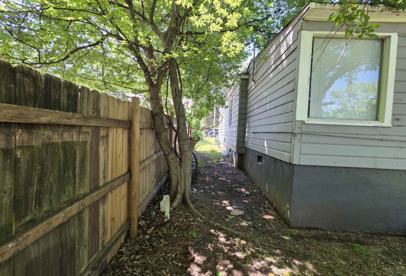 Property exterior with horizontal siding and a visible window, featuring a wooden fence alongside