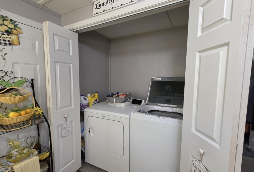 Dedicated laundry closet featuring a white washer and dryer set, neutral wall color, and wood-finish flooring