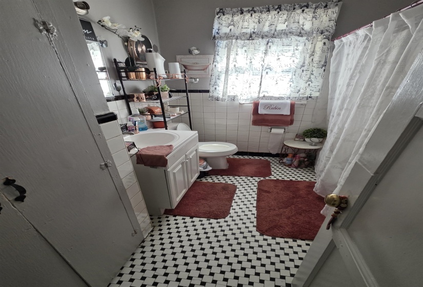 Bathroom featuring a white vanity with integrated sink, a commode, and white subway tile wainscoting