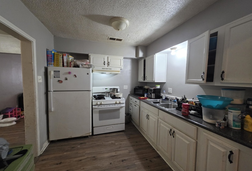 Kitchen with wood-finish flooring, white cabinetry, a double basin sink, and ample counter space