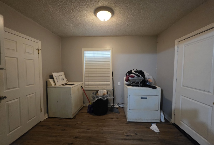 Dedicated laundry room featuring wood-finish flooring and a single window with blinds